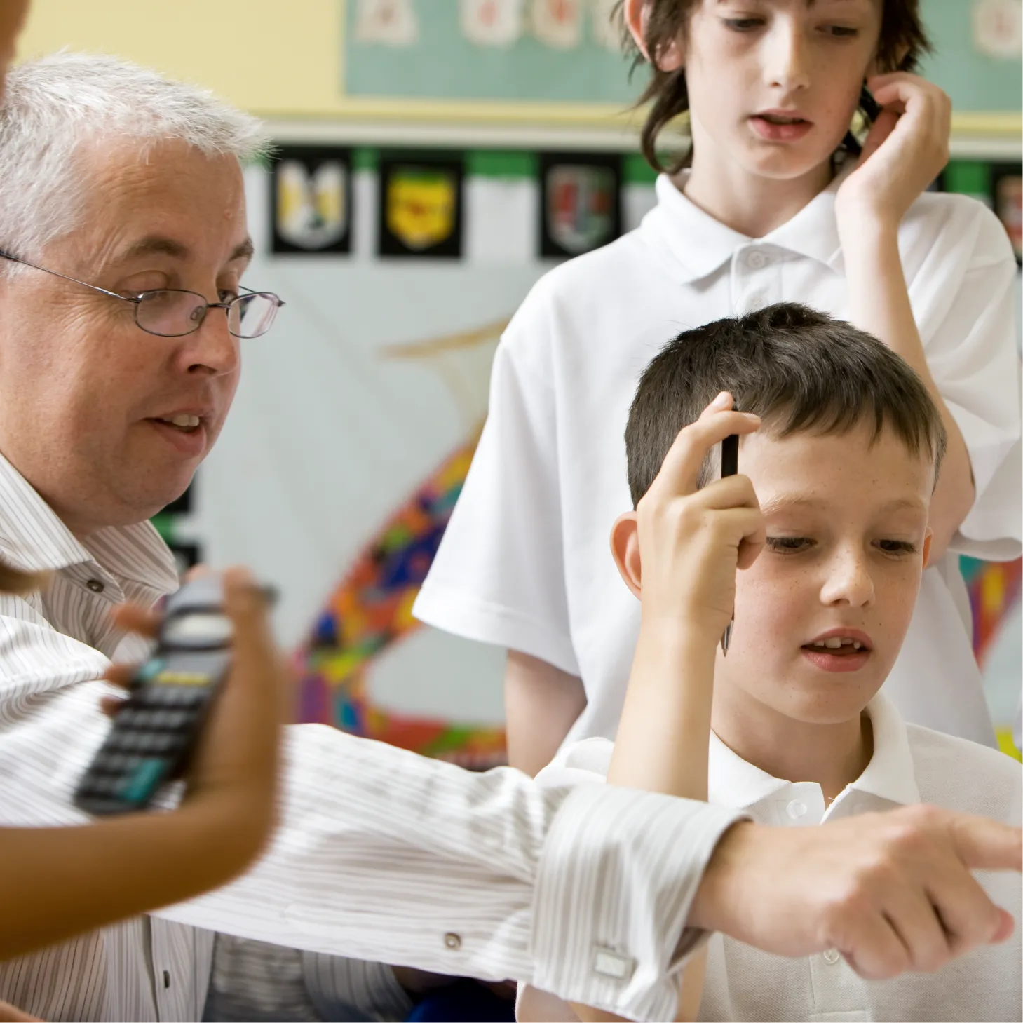 A teacher pointing to something to show three pupils.