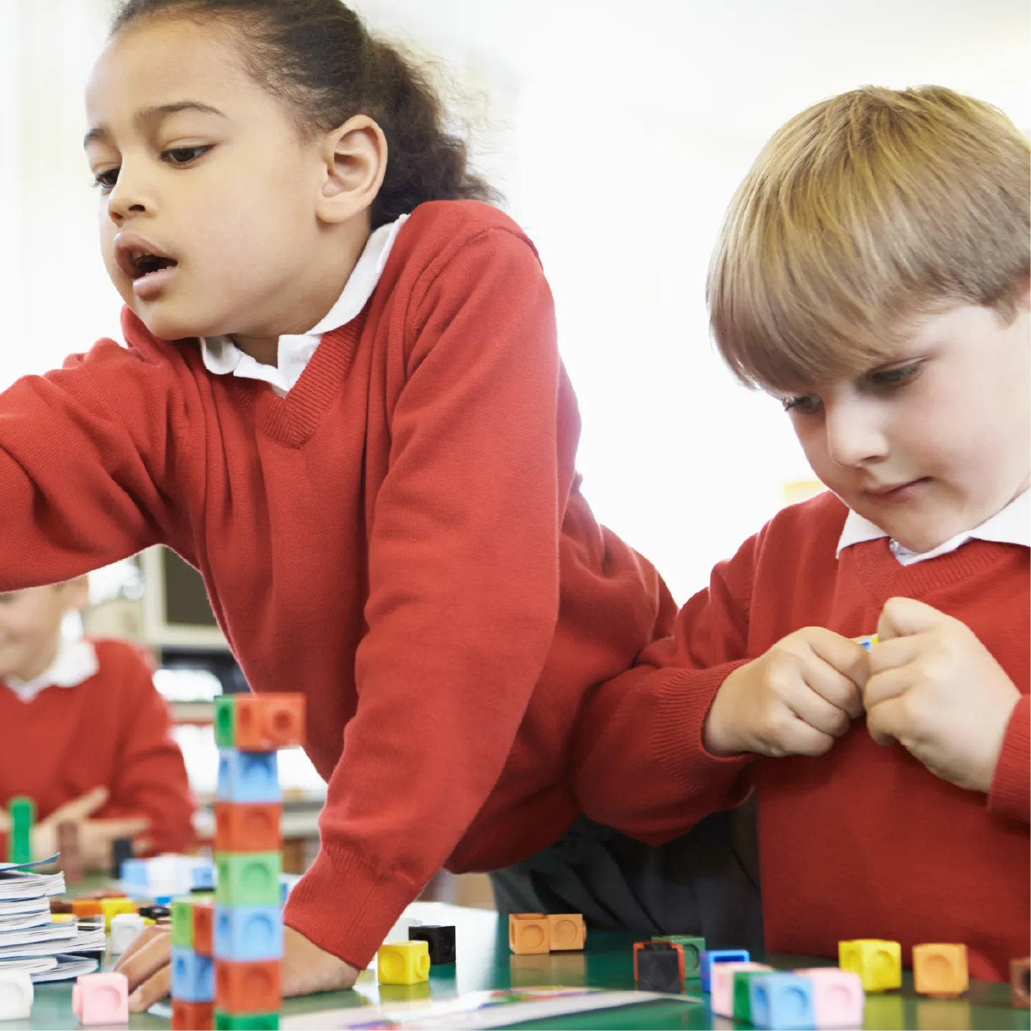 Two pupils building with maths manipulative blocks.