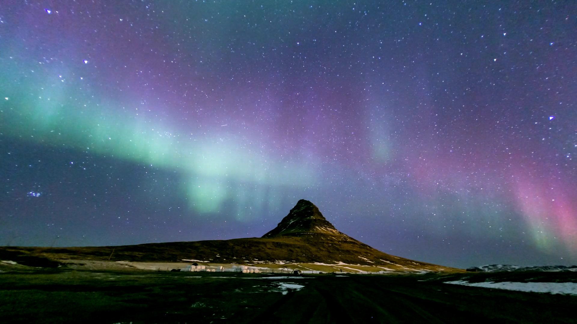 Aurora borealis over a mountain at night.