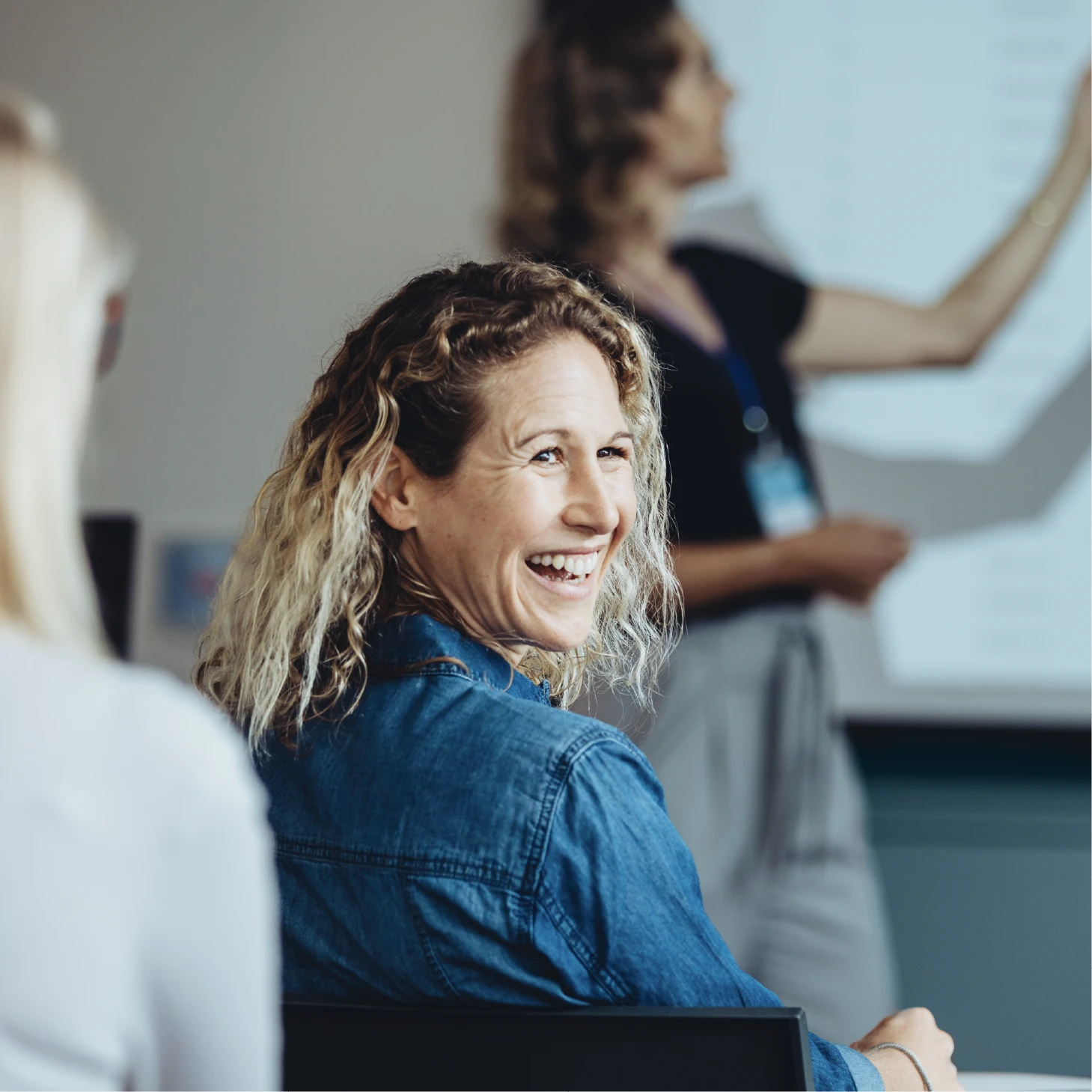 A lady with an enthusiastic smile turns to face someone behind her during a training session.