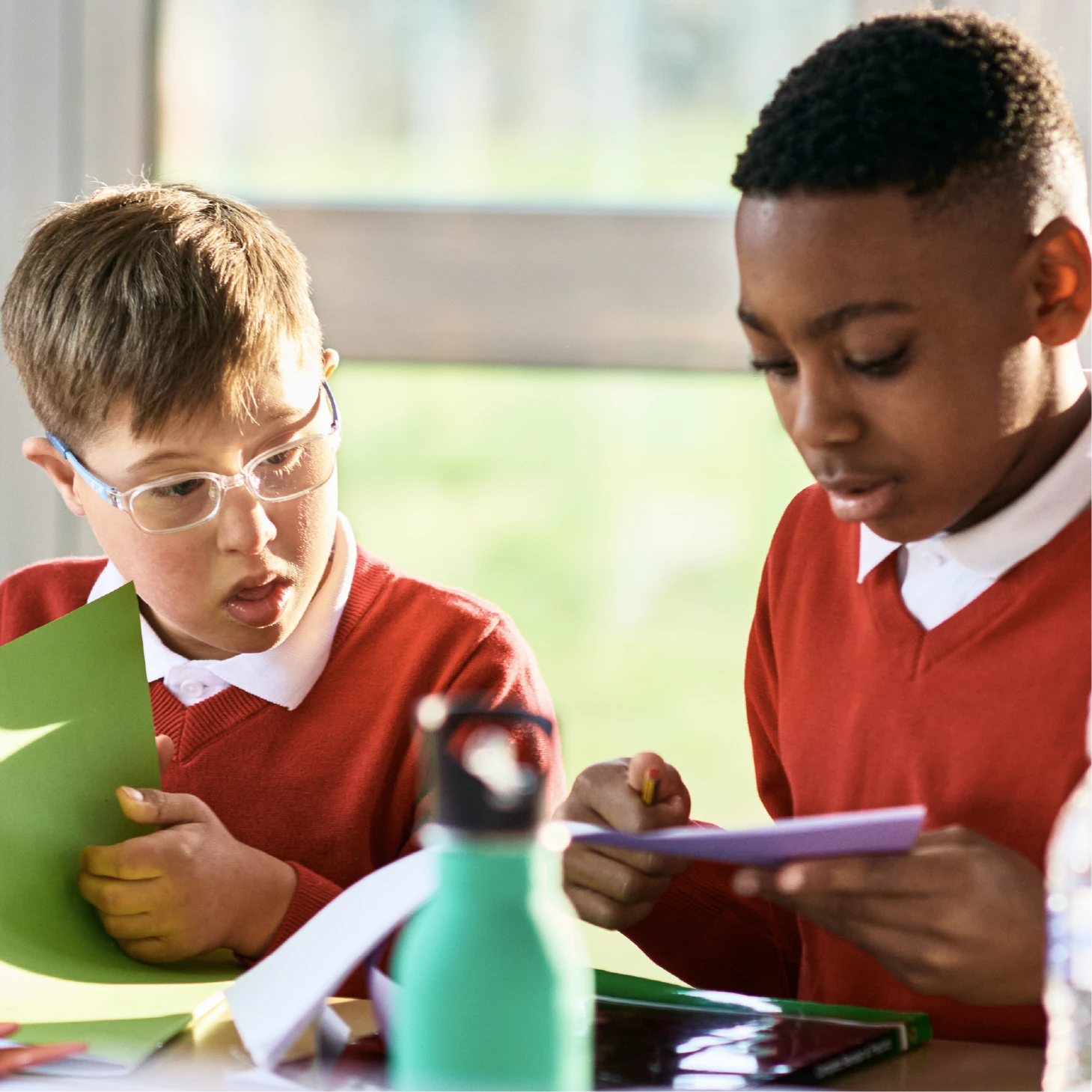 Two young primary school boys looking at a piece of work together.