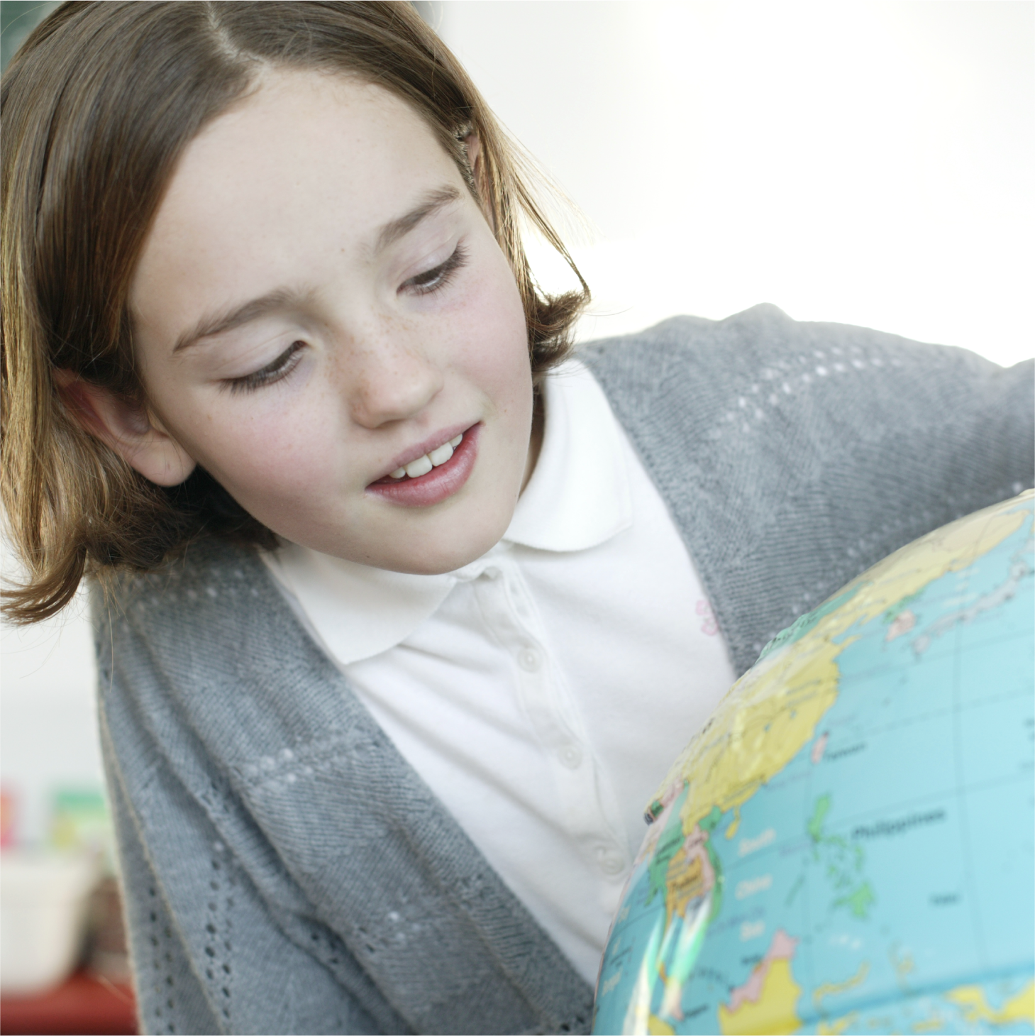 Pupil examining a globe in the classroom while learning about world geography.