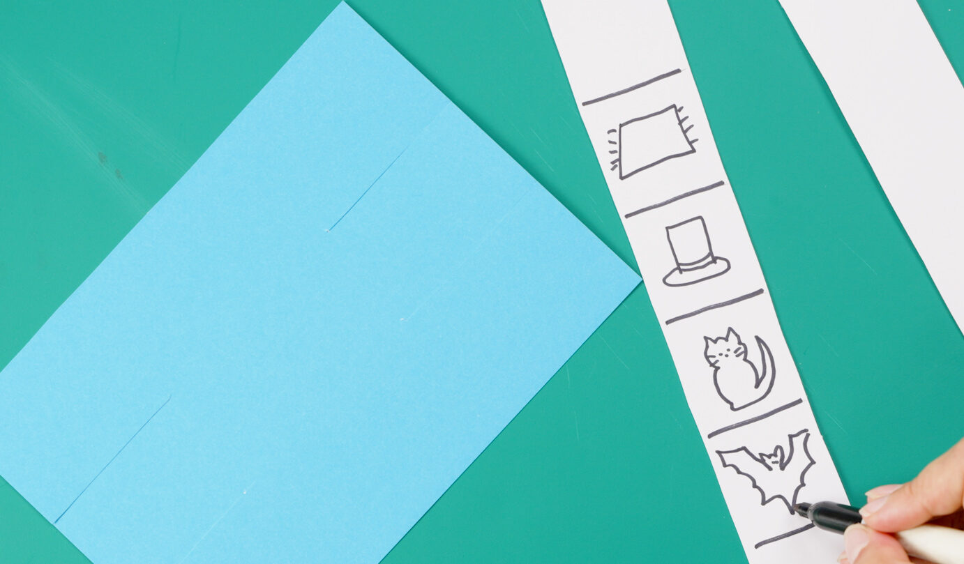Person drawing pictures on a strip of white card that forms the slider of a matching slider game