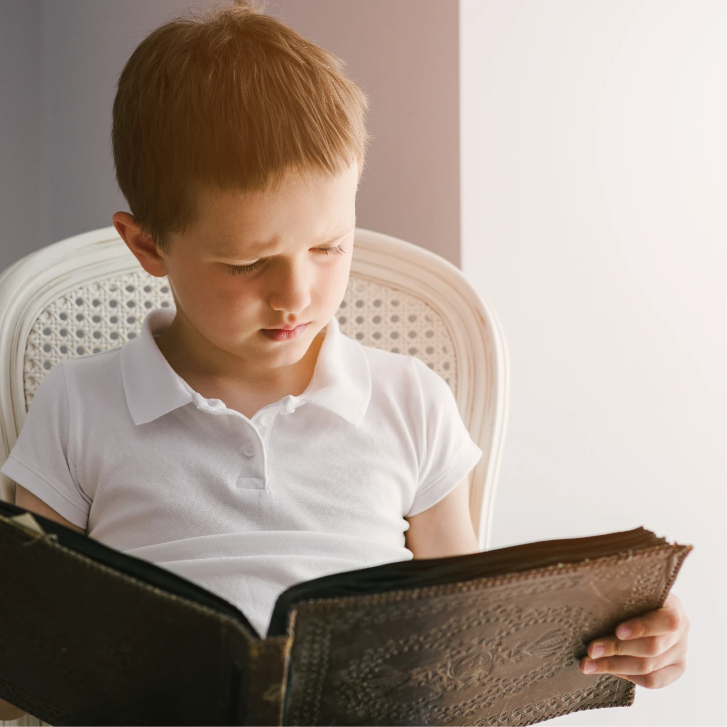 A young child sitting on a chair and reading a book.