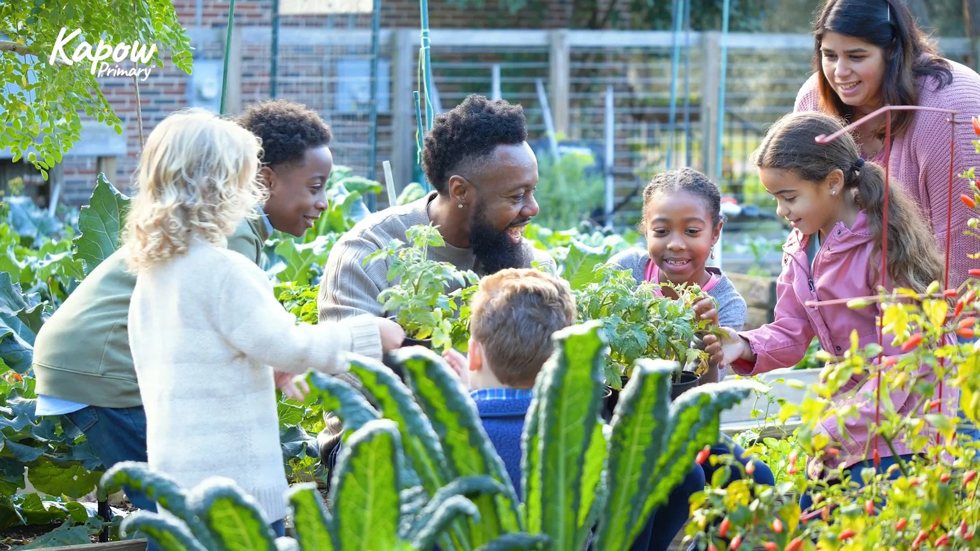 Group of pupils and adults gardening together in a school vegetable patch, smiling and engaged.