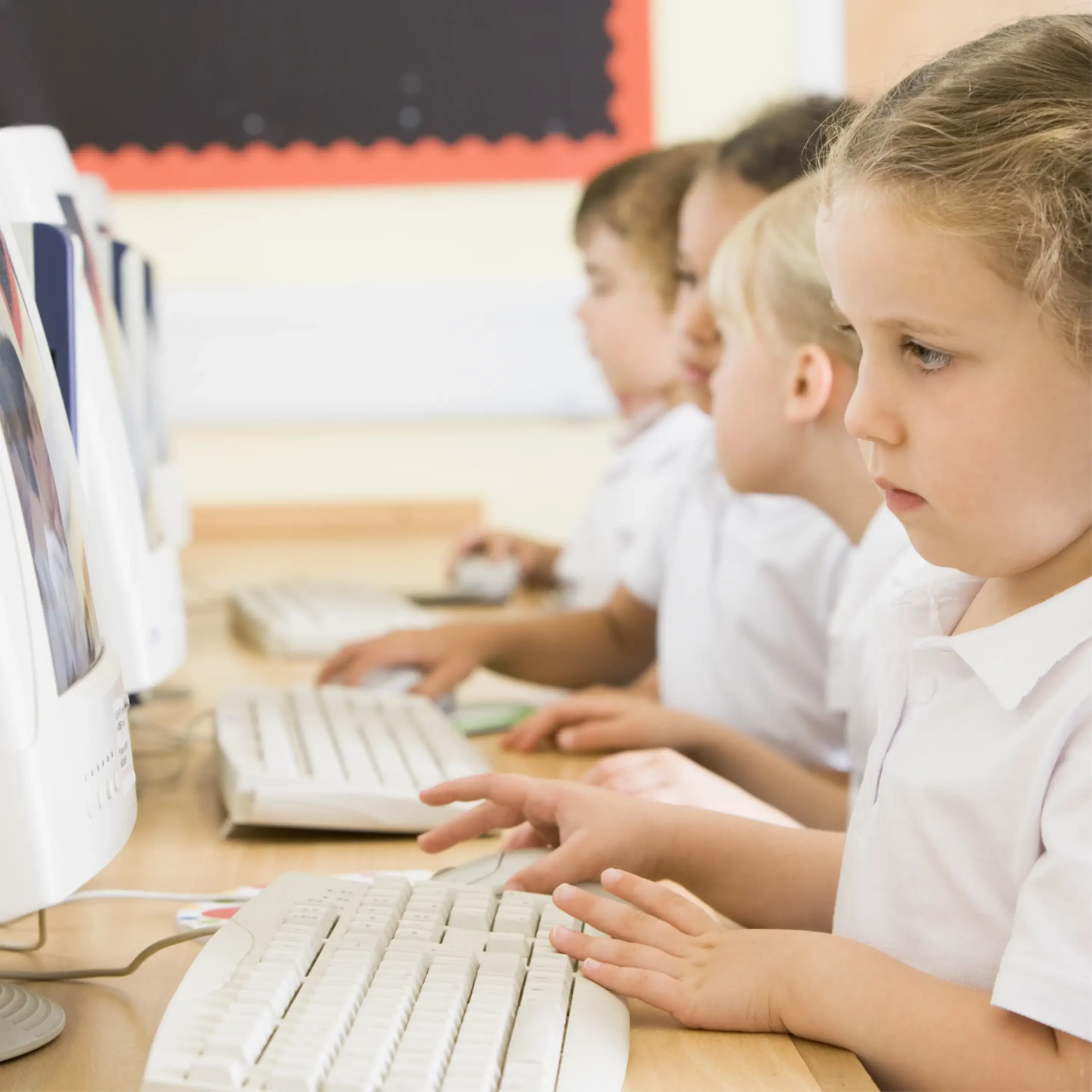 A row of pupils use computers in a classroom.
