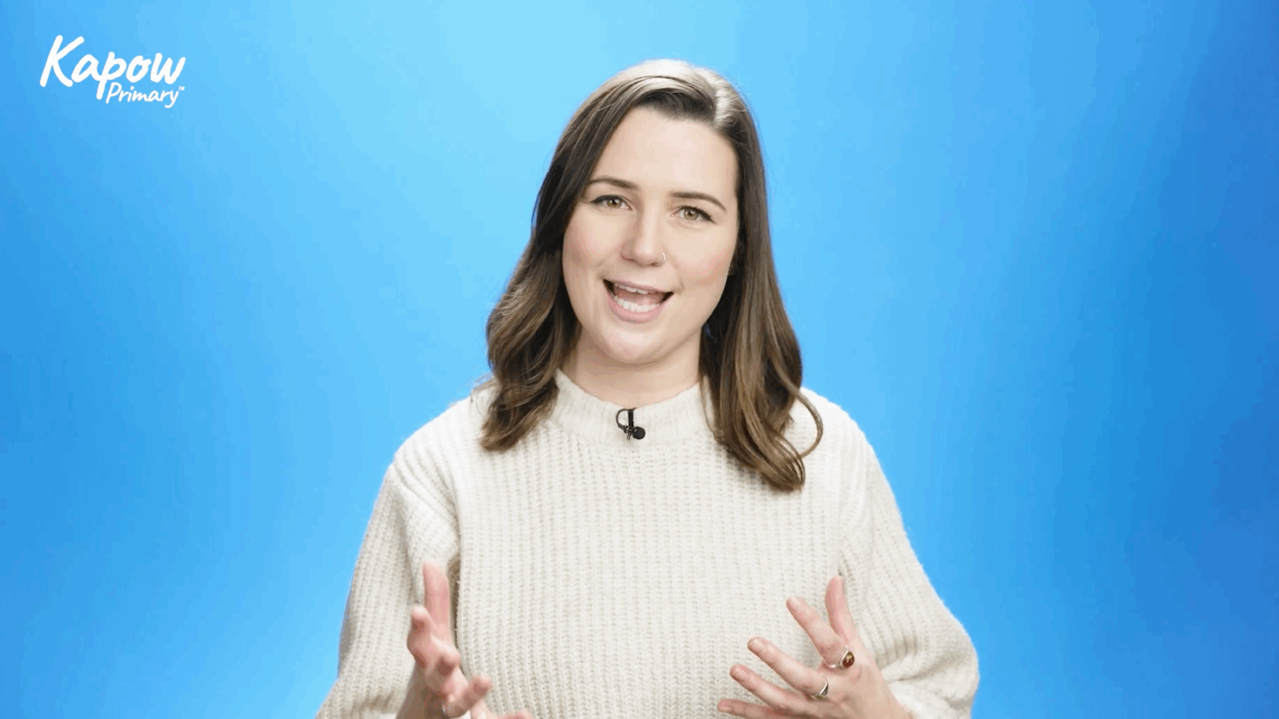 A smiling presenter gestures in front of a blue background.