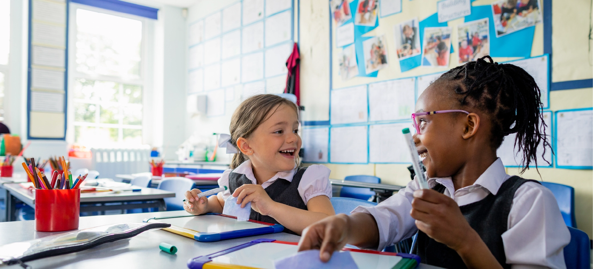 Two young girls laughing together while working in class.