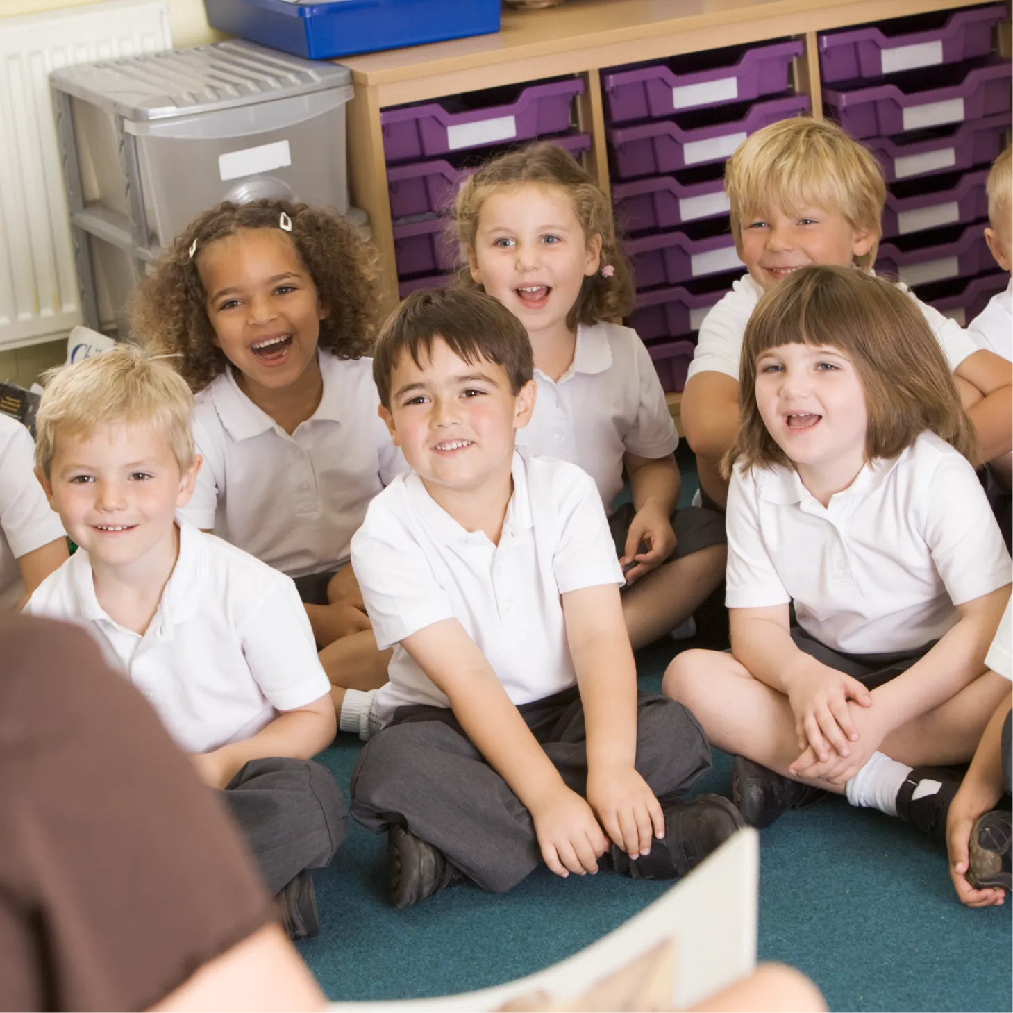 A group of primary school children sitting and smiling during a classroom activity