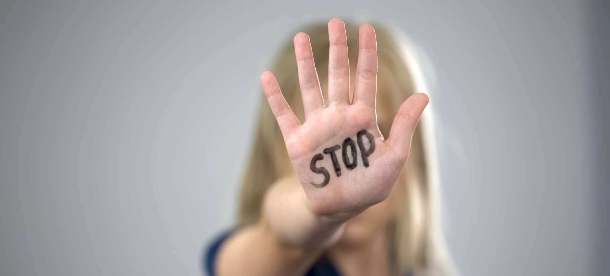 A raised hand with the word “STOP” written on the palm.