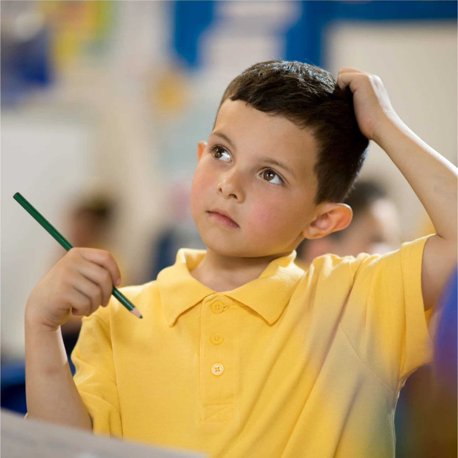 A child holding his hand to his head in thought, with a pencil in the other as he contemplates an answer.
